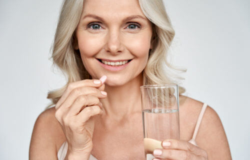 Woman holding vitamin or multivitamin pill