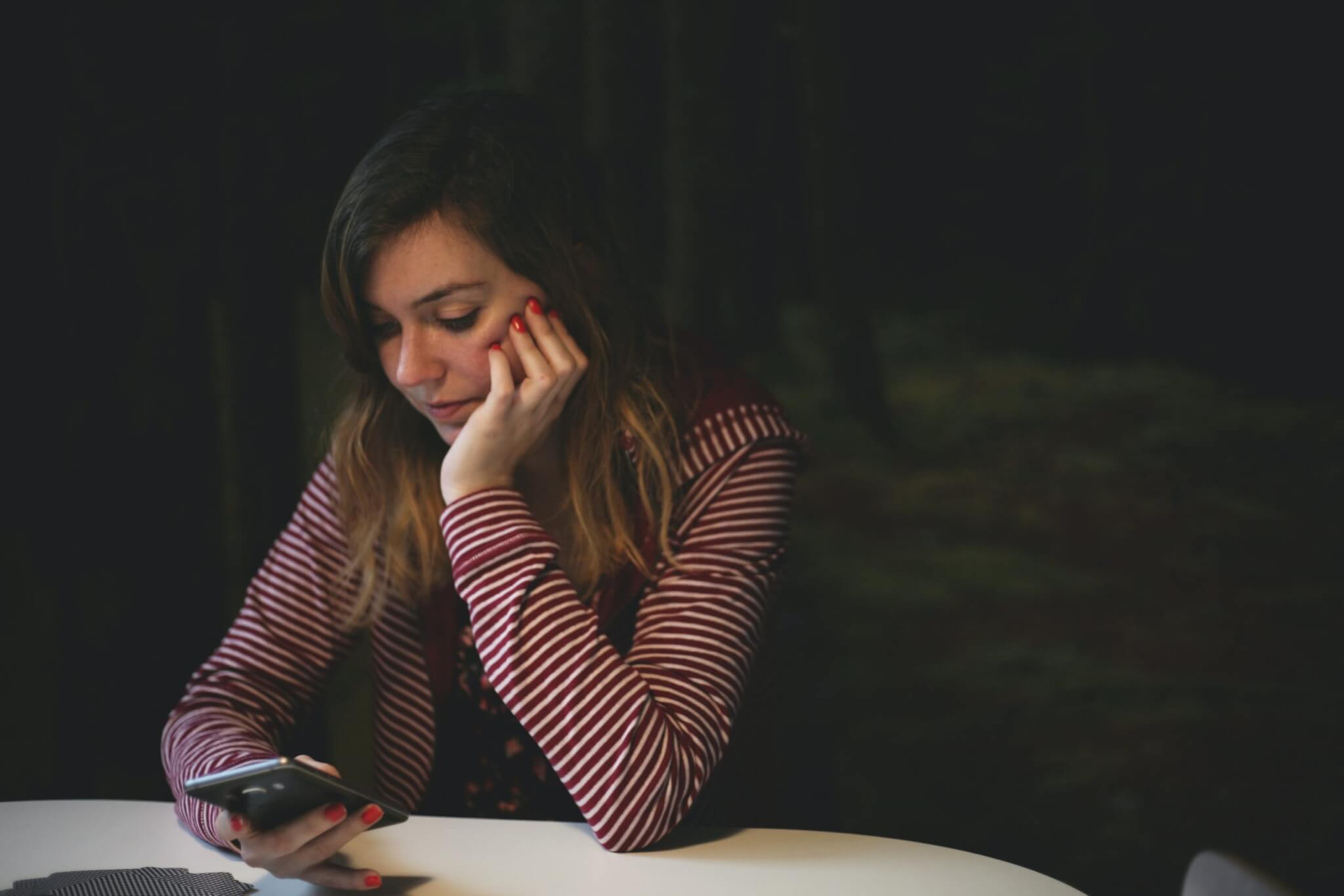 Woman alone, sad while looking at smartphone