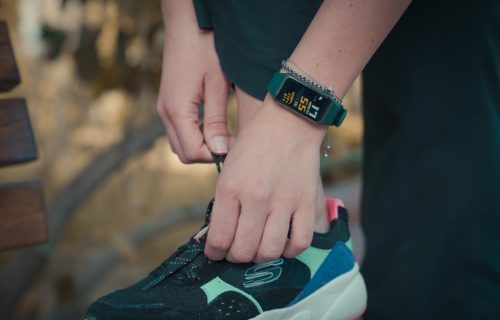 Runner lacing sneakers, wearing fitness tracker before exercising