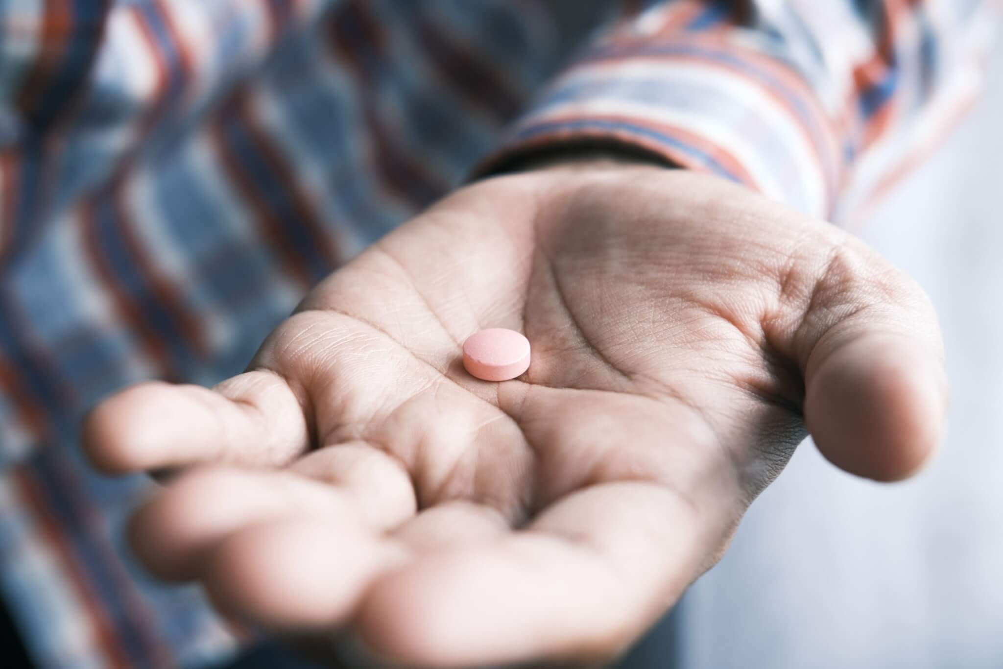 Man holding a pill or medication in his hand