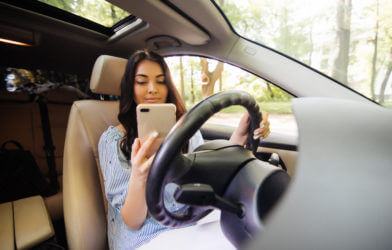 Teen or young woman using phone while driving car