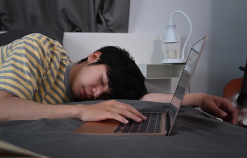 Teen asleep next to laptop computer on bed