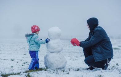 Man building a snowman with his child