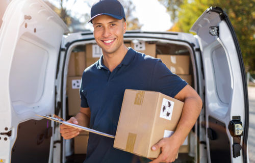 Delivery man standing in front of his van with packages