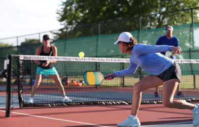 A woman hits a dink shot while playing pickleball.