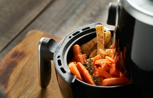 Cooking potatoes and carrot sticks with spices in an air fryer