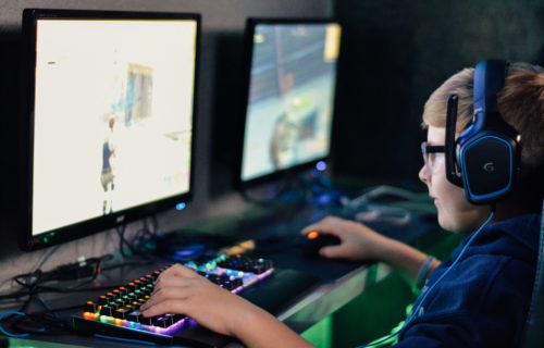 Boy wearing gaming headset while playing video games on the computer.