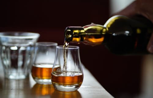 Bourbon whiskey being poured into glasses