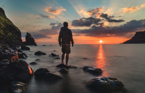 Man enjoying a dose of nature by watching a beautiful sunset or sunrise over the ocean