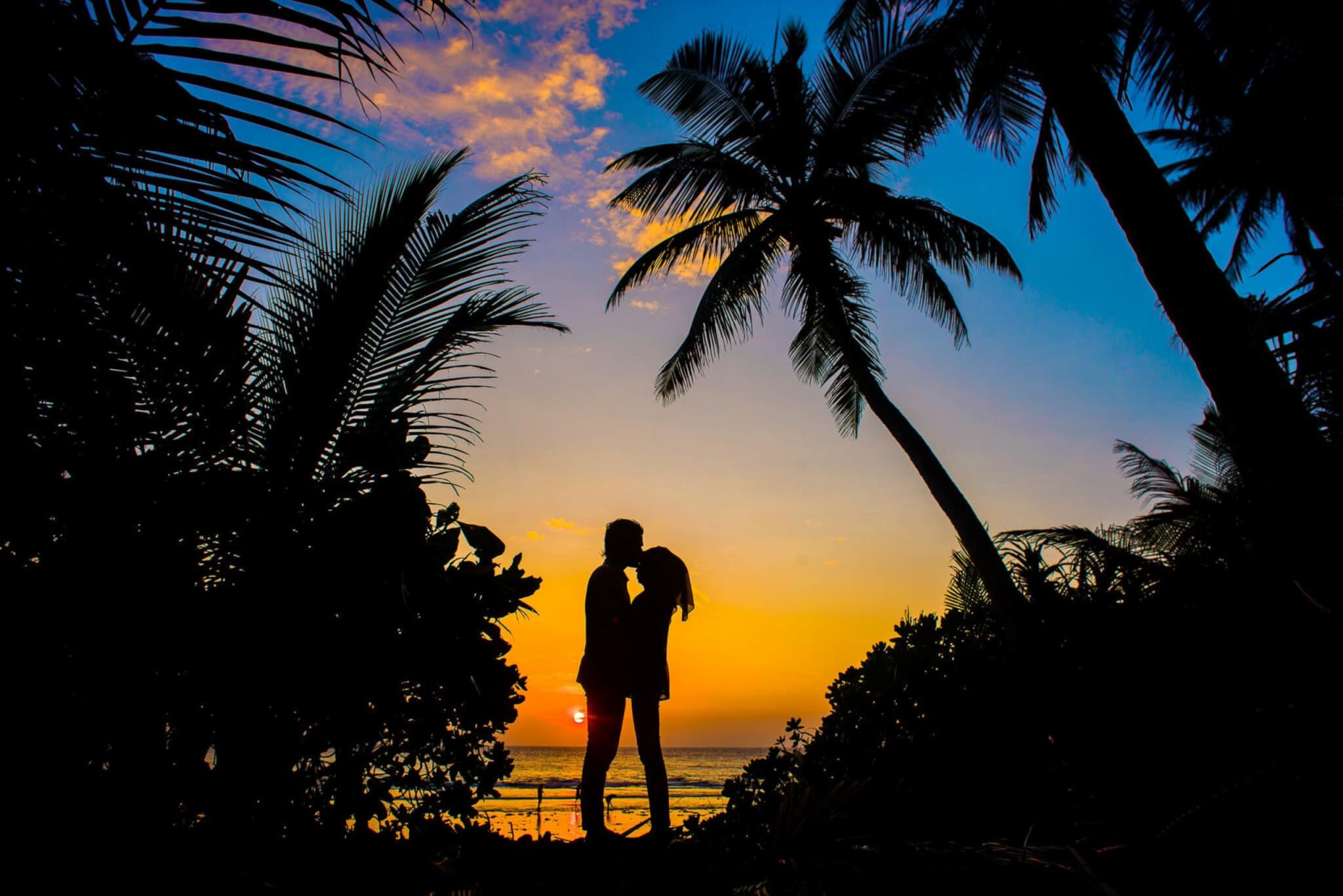 Couple kissing in front of sunset on beach vacation