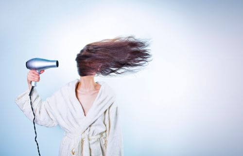 Woman blow drying her hair over her face