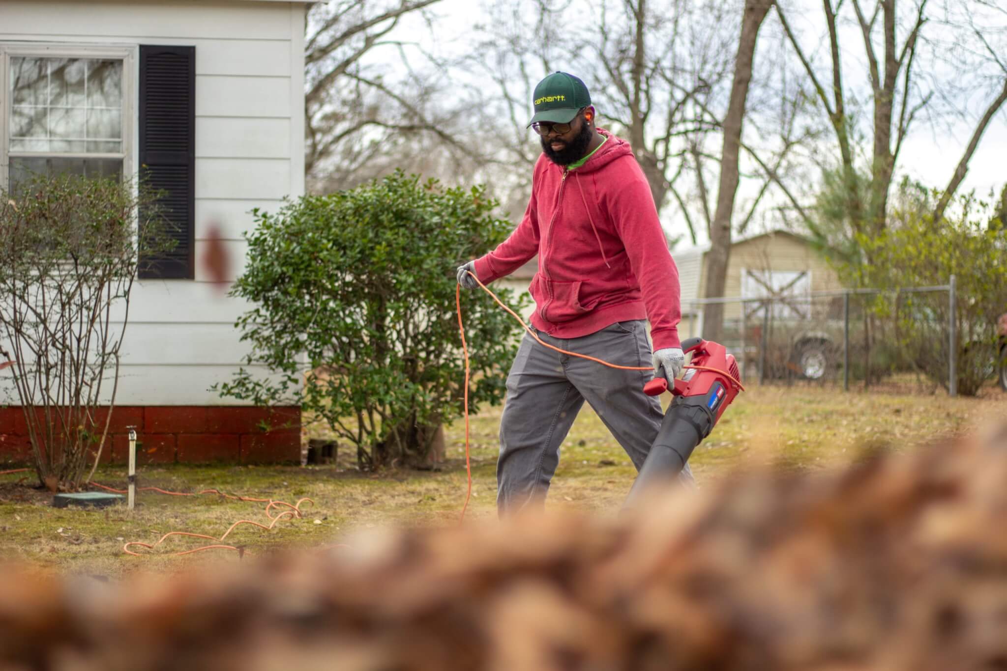 Man doing yard work, blowing leaves with leaf blower