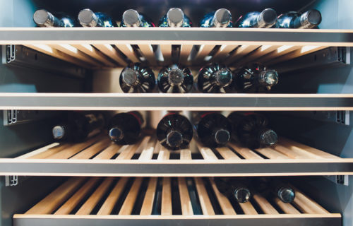 Wine fridge with several bottles on the racks.