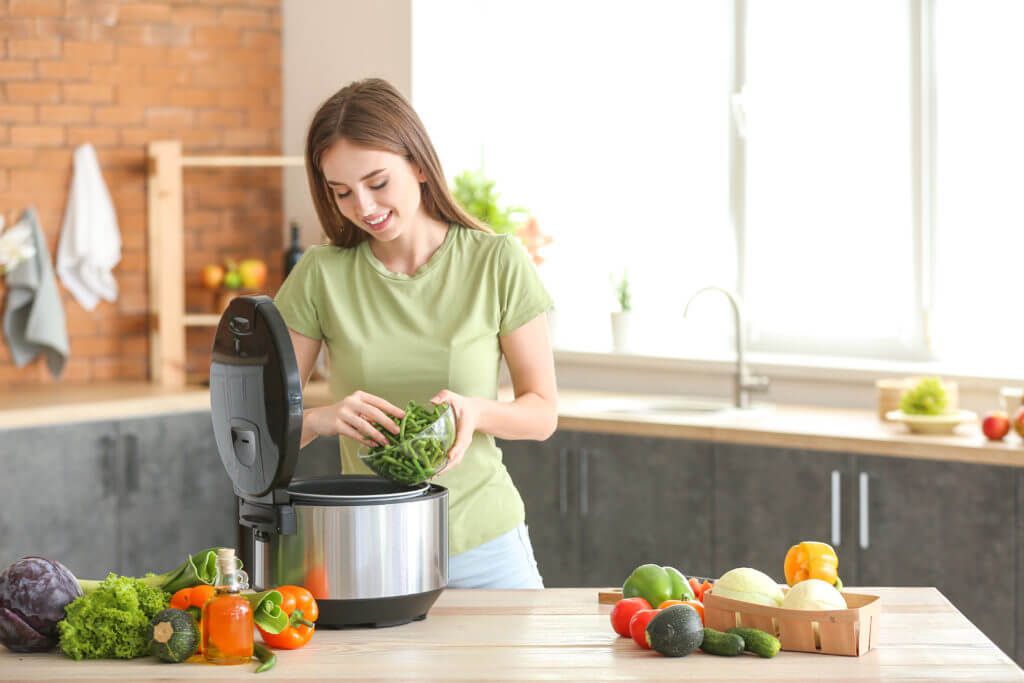 Woman cooking meal using slow cooker in kitchen