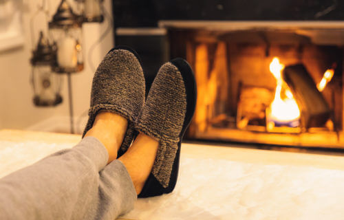 Man in slippers relaxing with his feet up by the fireplace