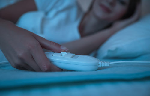 Woman in bed using an electric heated blanket