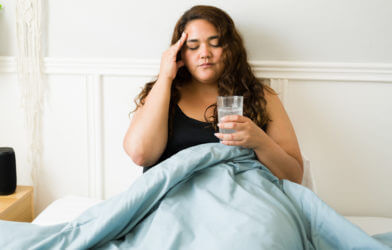 Stressed woman feeling sick, lying in bed.