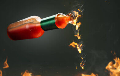 Hot sauce with fire droplets coming from bottle for spicy food
