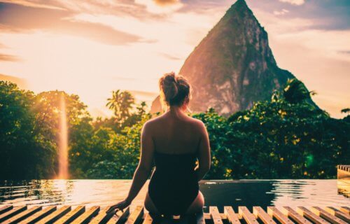 Woman sitting poolside at a resort in St. Lucia overlooking the Piton Mountains
