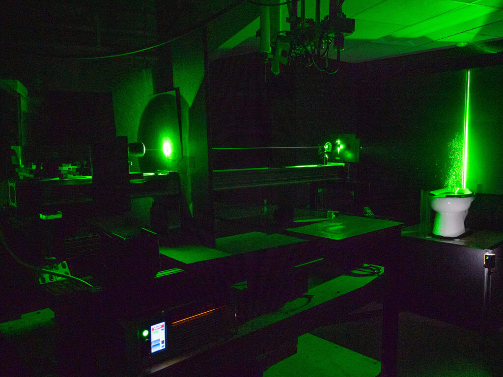 A powerful green laser helps visualize the aerosol plumes from a toilet