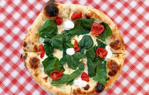 Delicious Italian pizza with spinach, cherry tomatoes, cream cheese and mozzarella in Napoli, Metropolitan City of Naples, Italy.