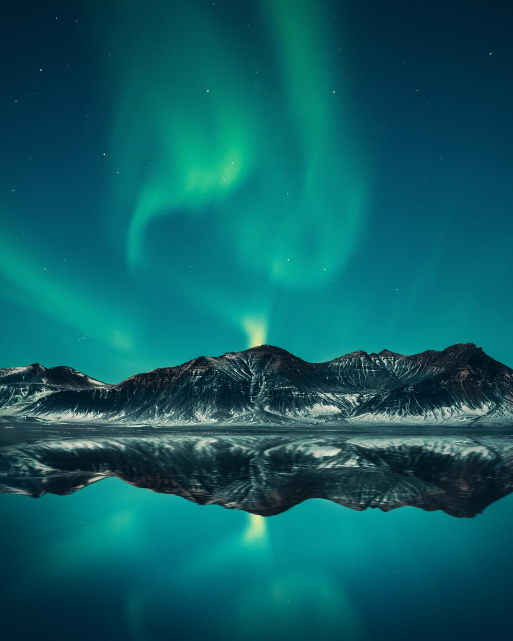 Green aurora over Iceland mountains.