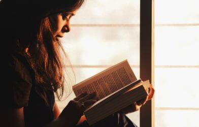 Woman reading a book by the window