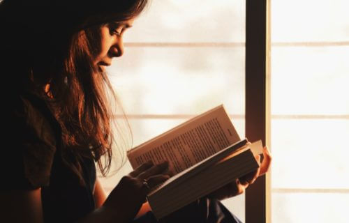 Woman reading a book by the window