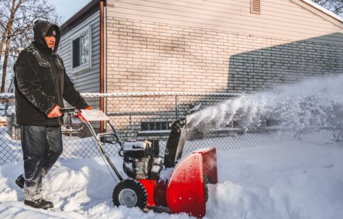 Man using a snow blower to clear the sidewalk