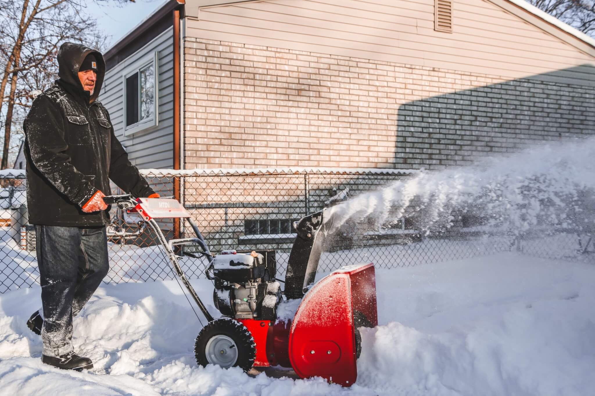Man using a snow blower to clear the sidewalk