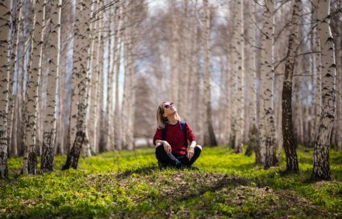 Woman sitting outside in forest, enjoying nature outdoors.