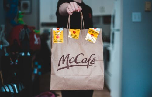 McDonald's worker holding a McCafe breakfast bag
