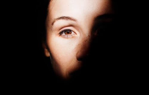 Woman's face half-covered by shadow so you can only see her eye