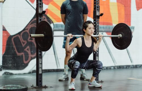 Woman doing barbell squats at the gym.