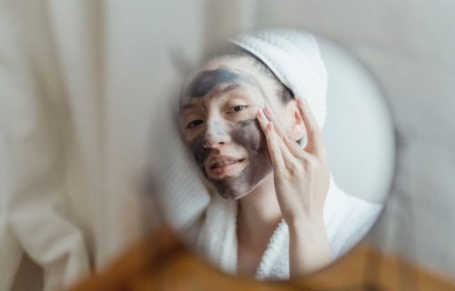 Woman rubbing in skin care face mask cream.