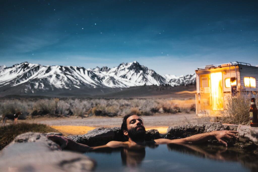 Man enjoying a hot stone bath outside of his van in Mammoth Lakes in Californi