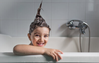 Child taking a bath with shampoo making hair stick up