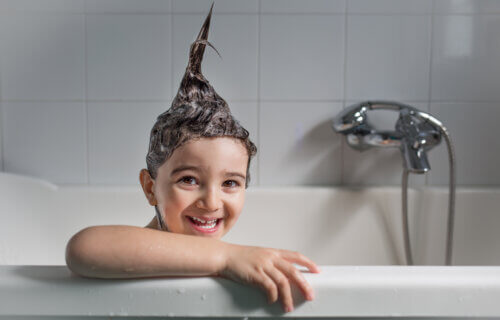 Child taking a bath with shampoo making hair stick up