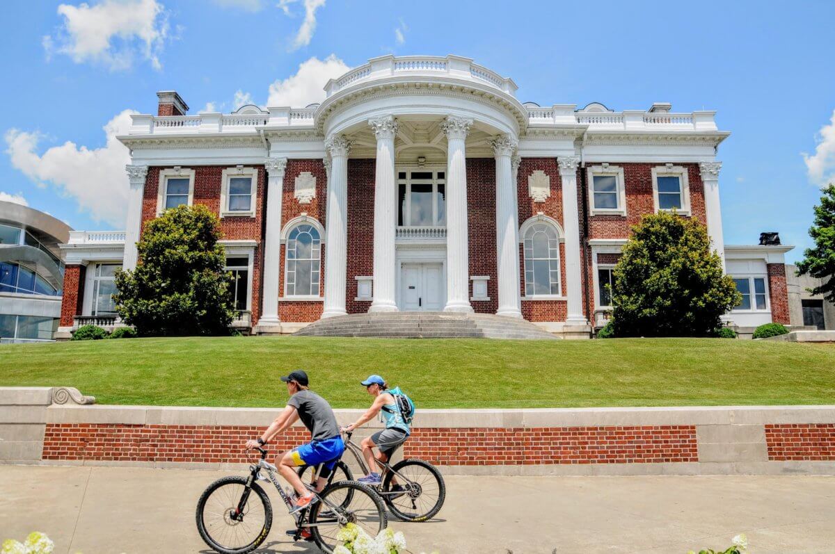 A couple rides bicycles in front of the Faxon-Thomas Mansion in Chattanooga