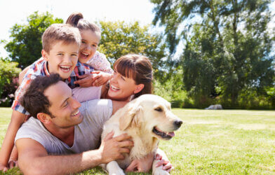 Family laughing and playing with dog outside