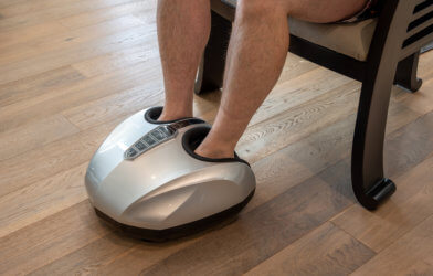 Man relaxing while having a foot massage on a machine at home