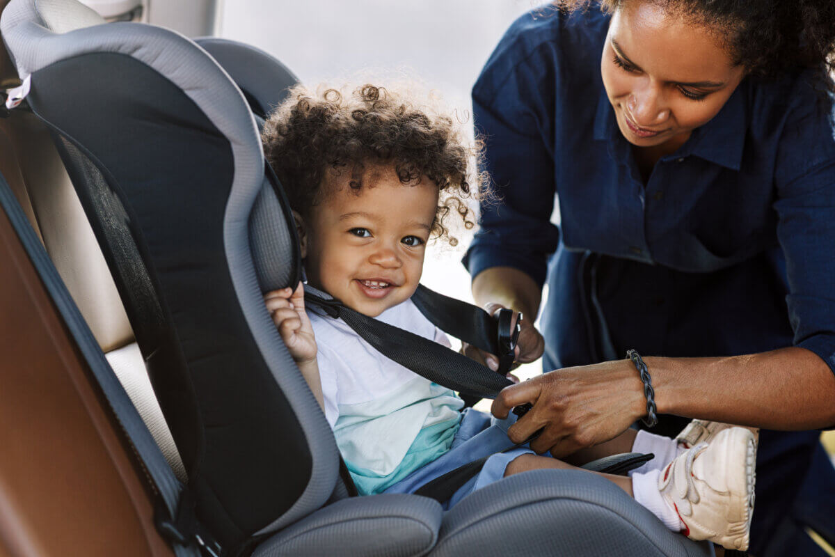 Mother placing child in car seat