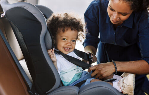Mother placing child in car seat