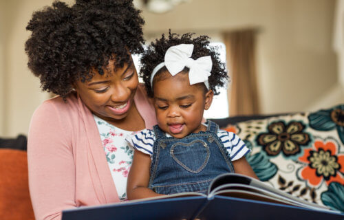 Woman reading a children's book to her young daughter