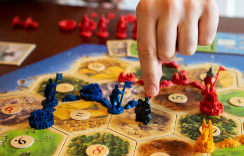 Close-up of person playing the board game Catan
