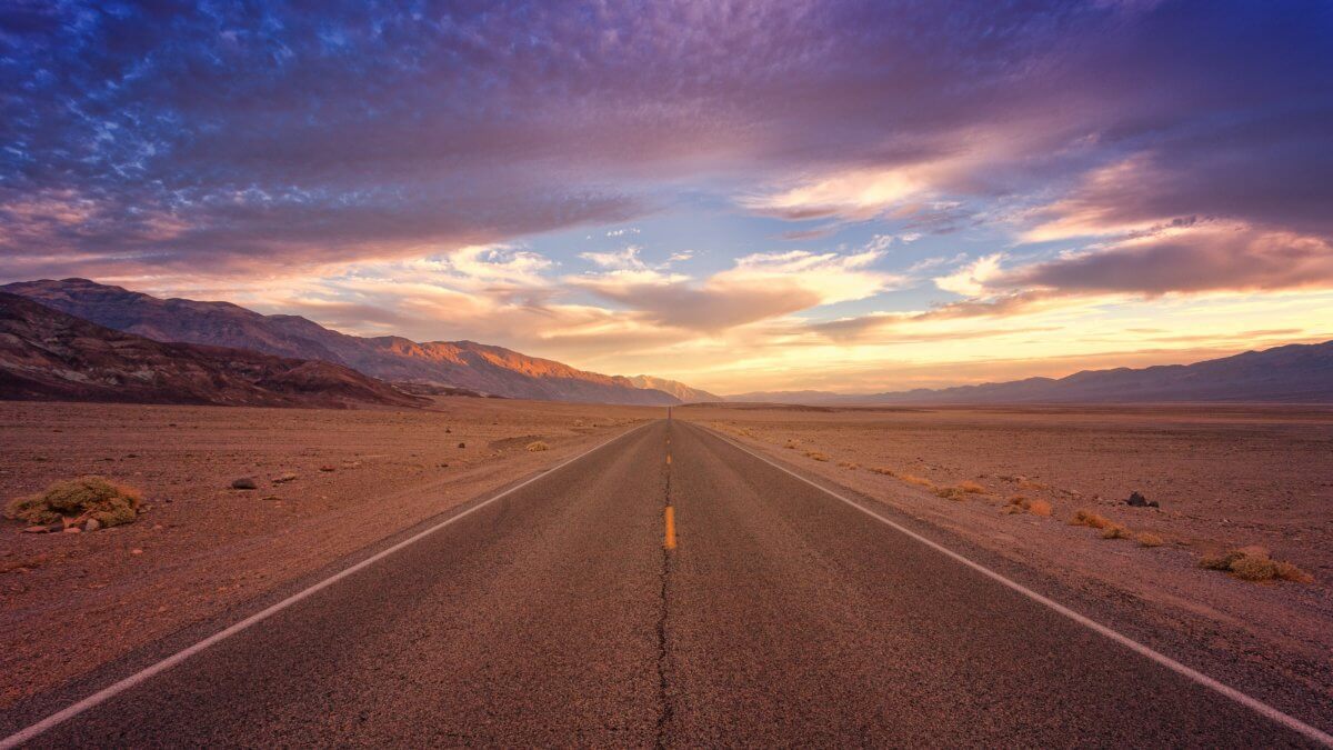 The sun is setting over the deserted roads of Death Valley, California