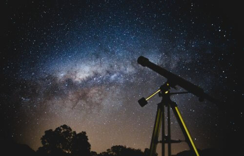 Telescope looking out at stars and planets in spectacular night sky