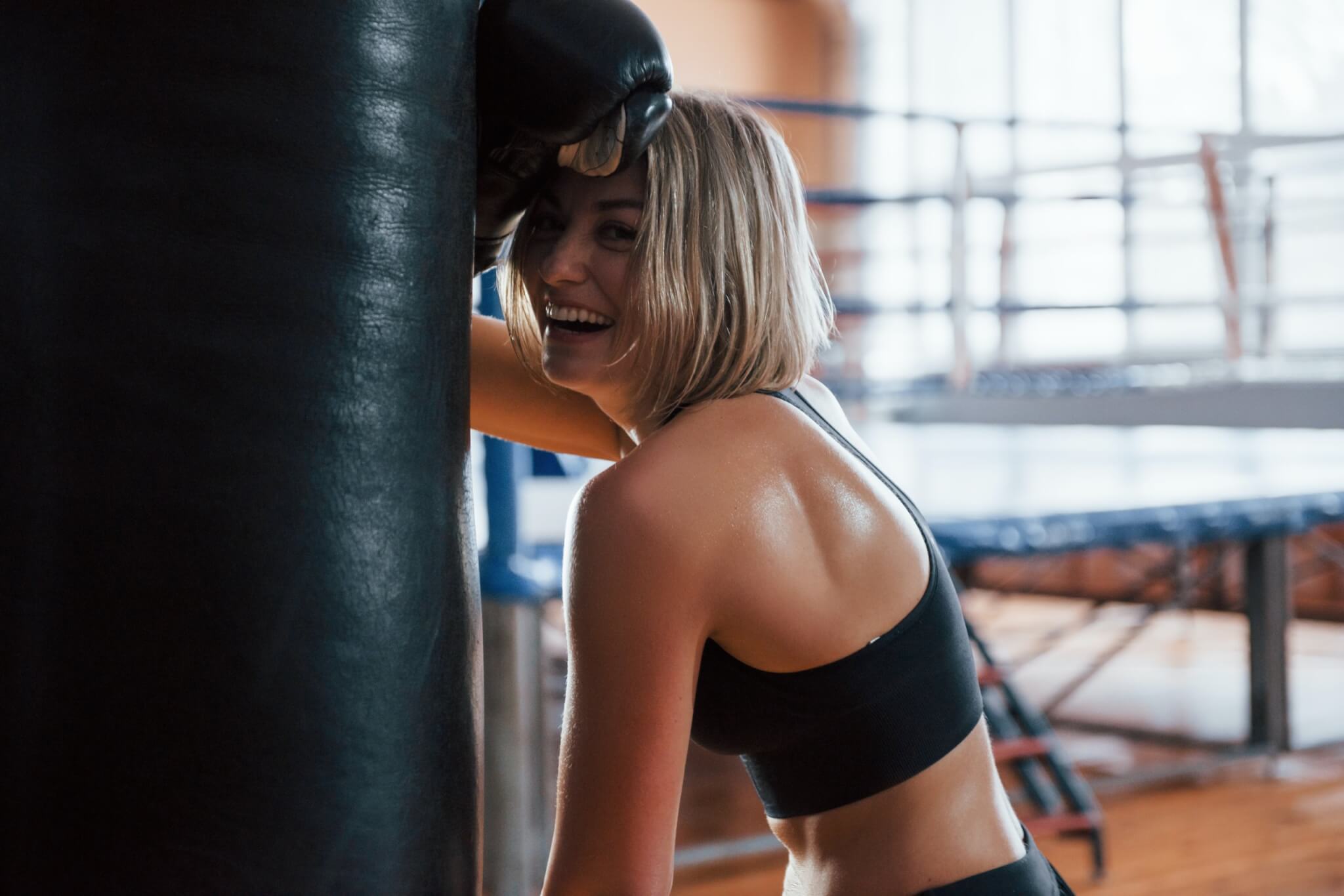 Woman at the gym laughing after finishing a strenuous boxing exercise