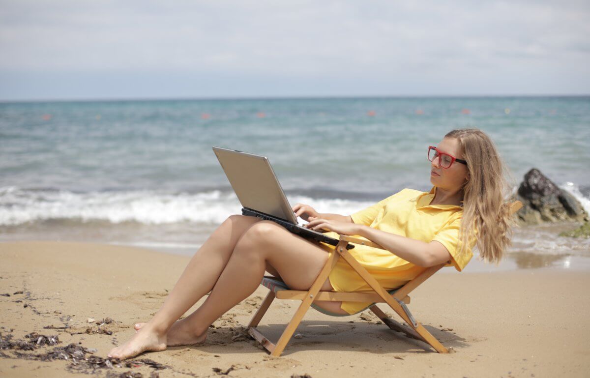 Woman working on her laptop while on the beach