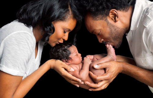 Newborn baby being held and kissed by parents